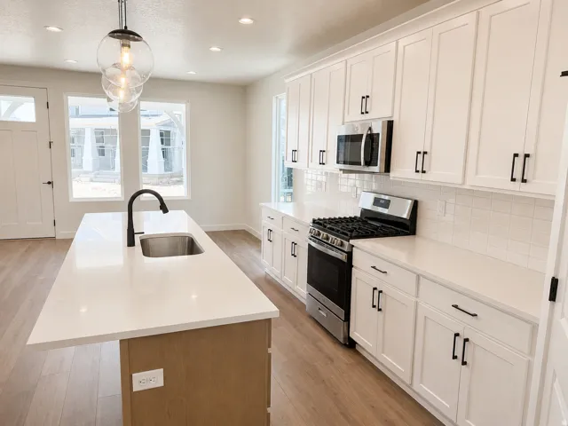 Modern kitchen featuring a central island with an undermount sink and matte black faucet