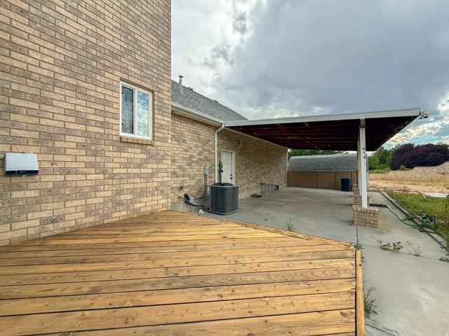 Expansive wood deck with a brick exterior, featuring a covered patio structure supported by brick pillars