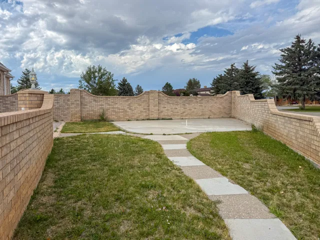 Curved brick privacy wall with decorative capstones, featuring an integrated lantern fixture and a paved patio area