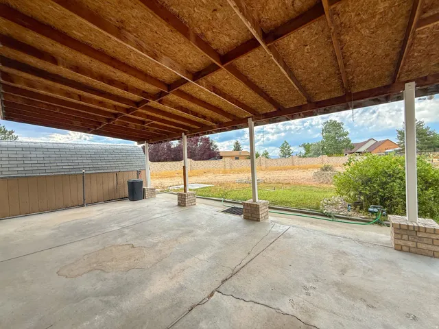 Covered patio featuring a wood-finish ceiling, exposed beams, and concrete flooring