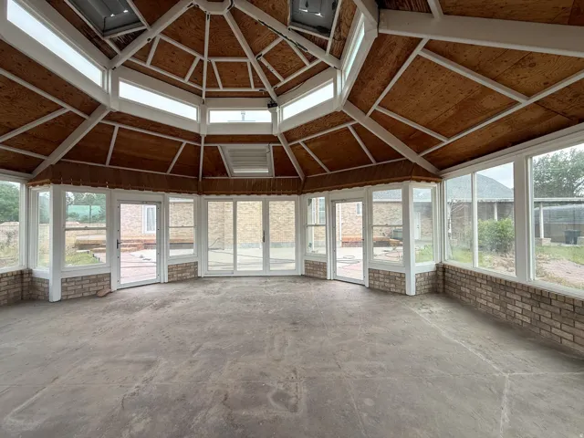 Octagonal sunroom featuring a concrete floor and perimeter brick wainscoting