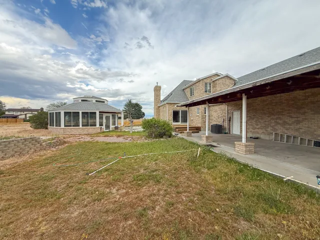 Brick exterior featuring a covered carport with brick pillars, a sunroom with multiple windows, and a raised wood-finish deck