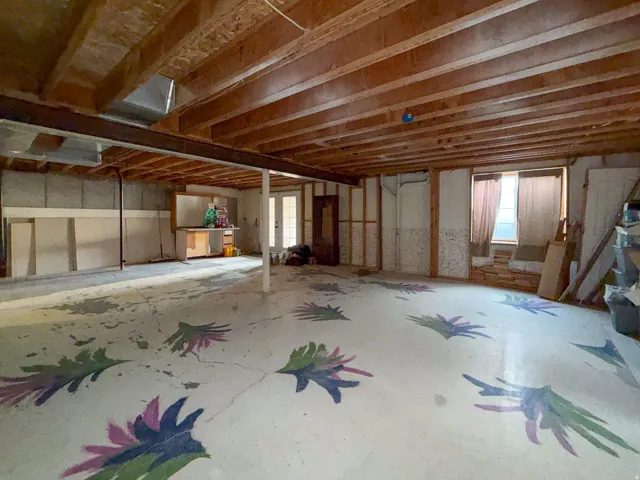 Spacious unfinished basement offering exposed wood joists, concrete flooring, and a steel support beam