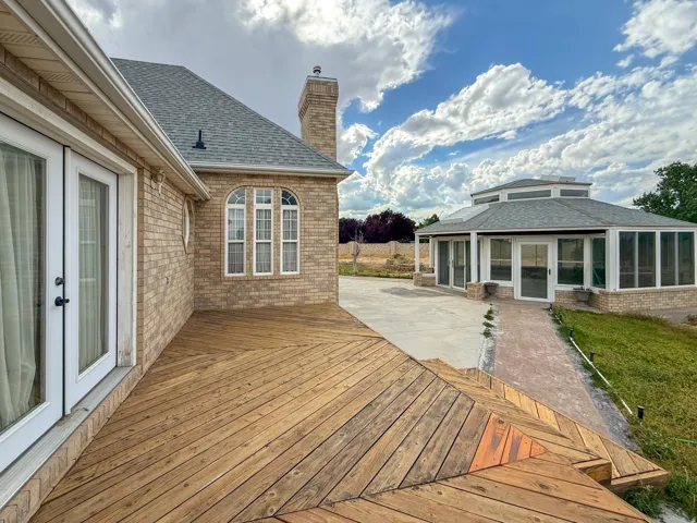 Expansive wood-finish deck with a geometric pattern, double French doors, and an arched transom window