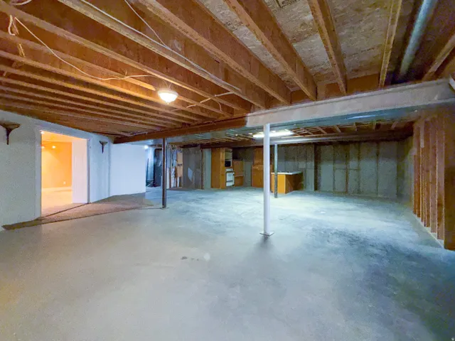 Expansive unfinished basement featuring concrete flooring and exposed ceiling joists