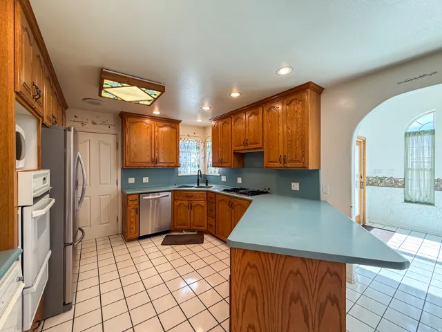 Kitchen featuring abundant wood cabinetry, an integrated stainless steel dishwasher, a stainless steel refrigerator, a double wall oven, and a gas cooktop