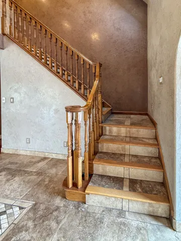 Wood-finish staircase featuring turned balusters and a contrasting wall finish