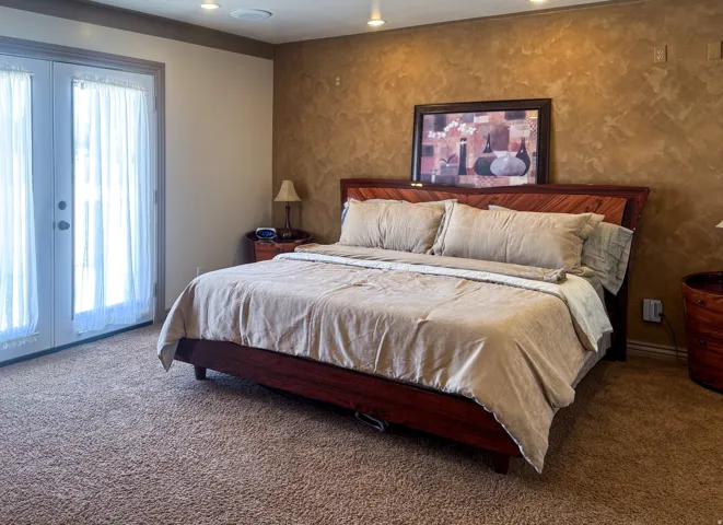 Bedroom featuring a textured accent wall, recessed lighting, and direct access to outdoor space via double French doors