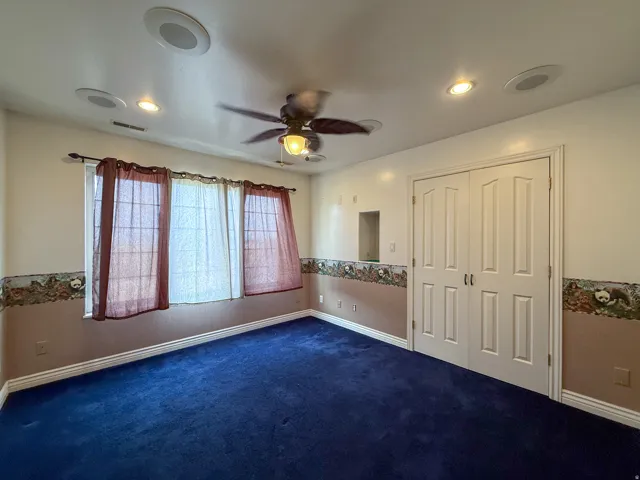 Room with blue carpet flooring, two windows, recessed lighting, and a ceiling fan