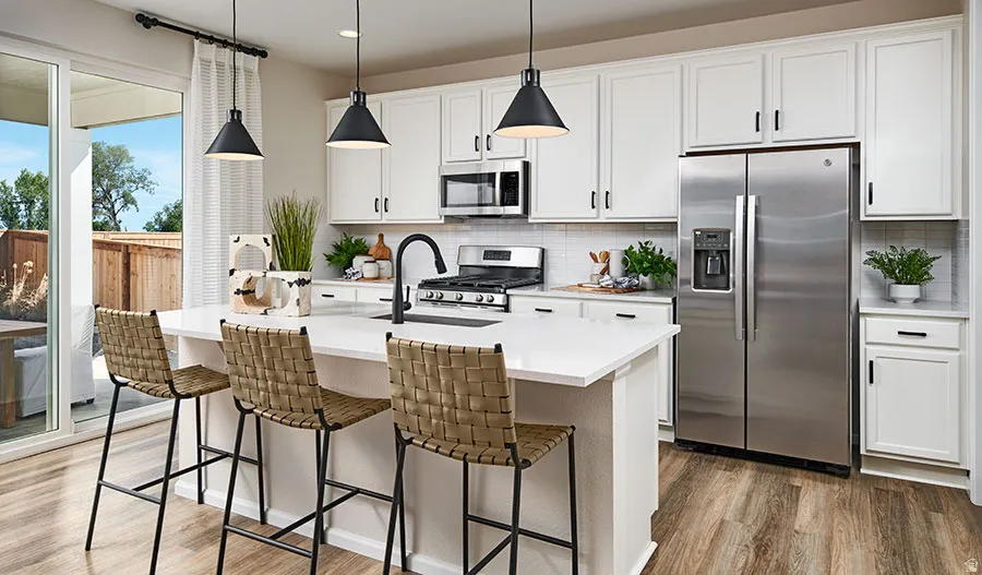Kitchen featuring a central island with countertop seating, white shaker-style cabinetry, stainless steel appliances, and wood-finish flooring