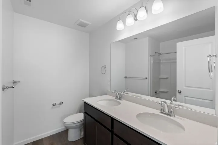 Dual vanity with white countertop, chrome fixtures, and a large mirror with overhead lighting