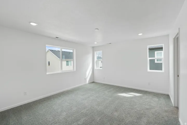 Recessed ceiling lighting, gray carpeting, and multiple windows