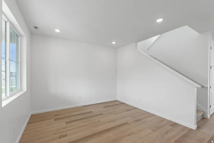 Recessed lighting, wood-finish flooring, white walls, white window trim, and a carpeted staircase