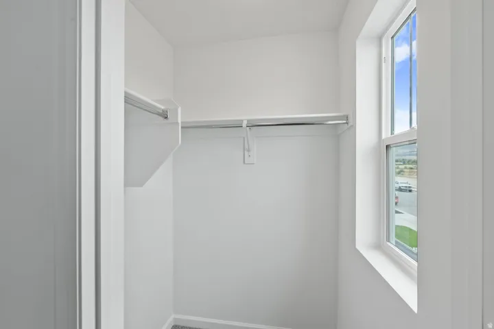 Built-in shelving and hanging rods, white walls, and a single-pane window
