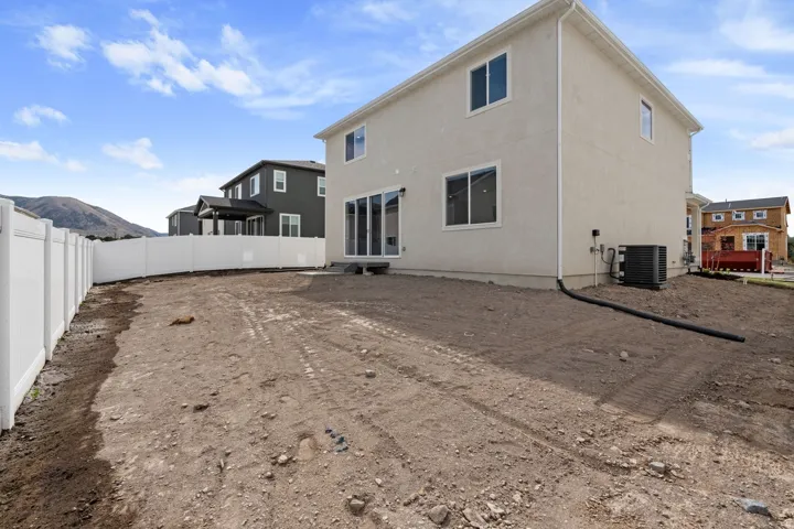 Rear exterior with a stucco finish, multi-pane windows, and a white vinyl fence