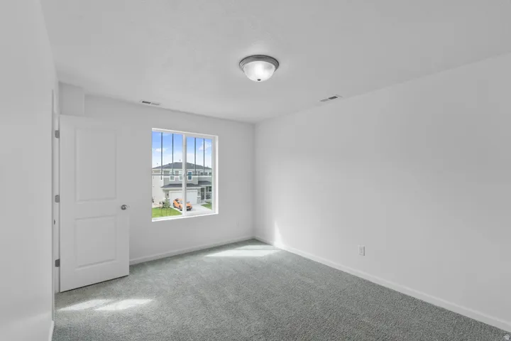 Bright interior space featuring light-colored walls, a ceiling-mounted light fixture, and textured carpeting