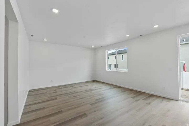 Recessed ceiling lighting, wood-finish flooring, white painted walls, and a sliding glass door