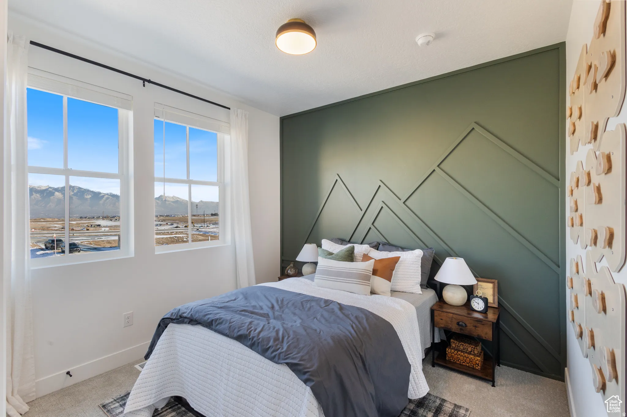 Bedroom featuring a decorative accent wall with geometric molding, two large windows, and neutral carpeting