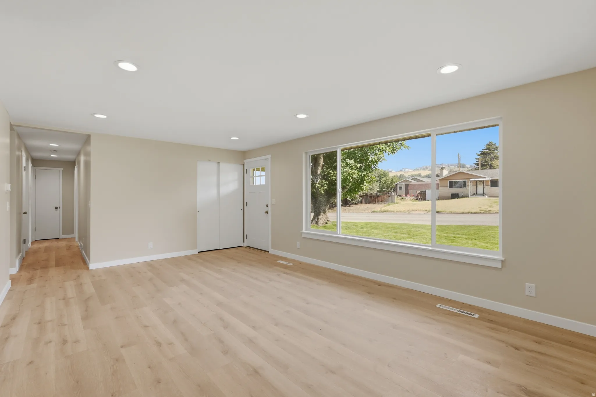 Spacious room featuring light wood-finish flooring and a large picture window