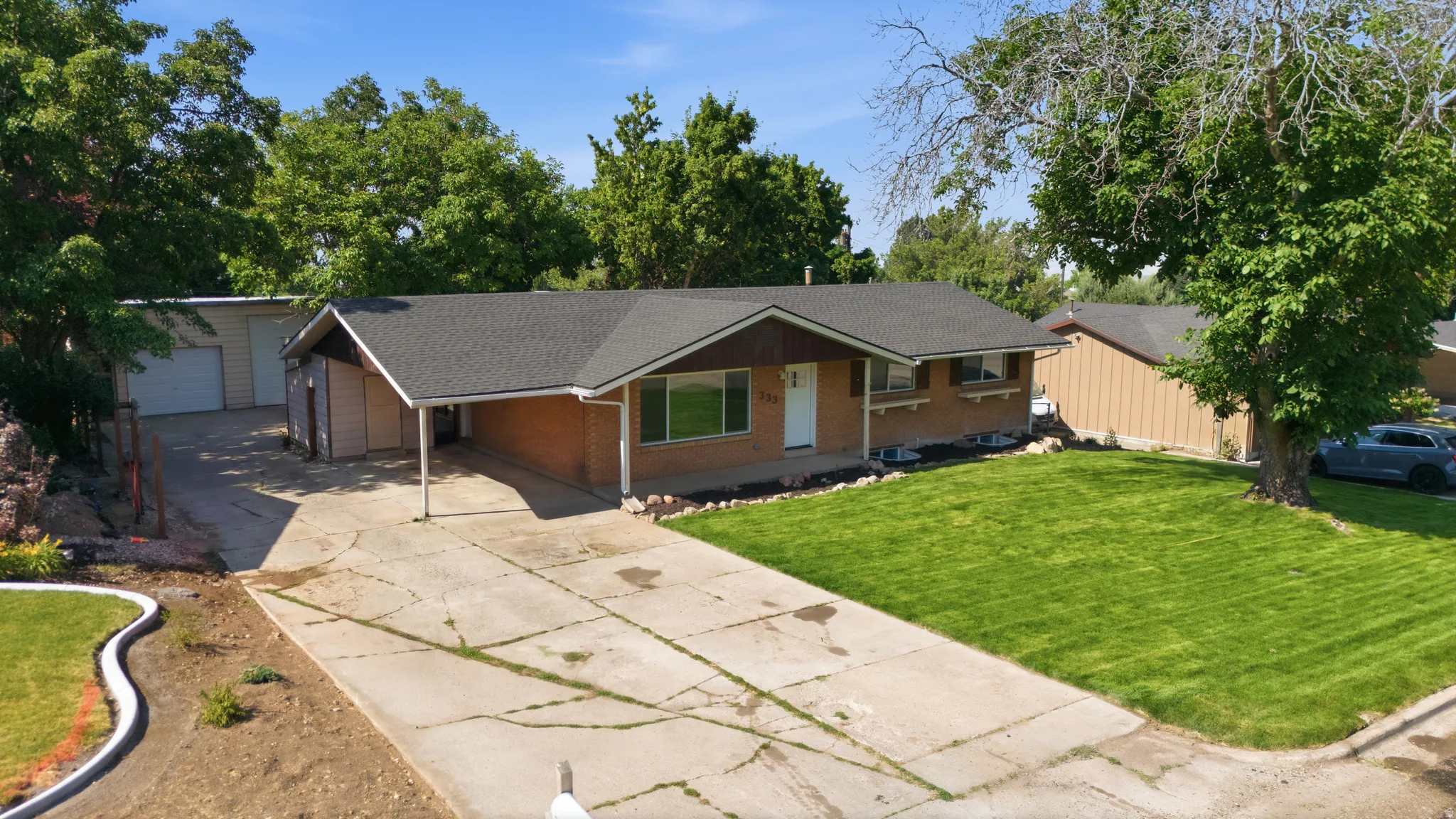 Ranch-style exterior with brick siding, a dark shingle roof, and a covered carport