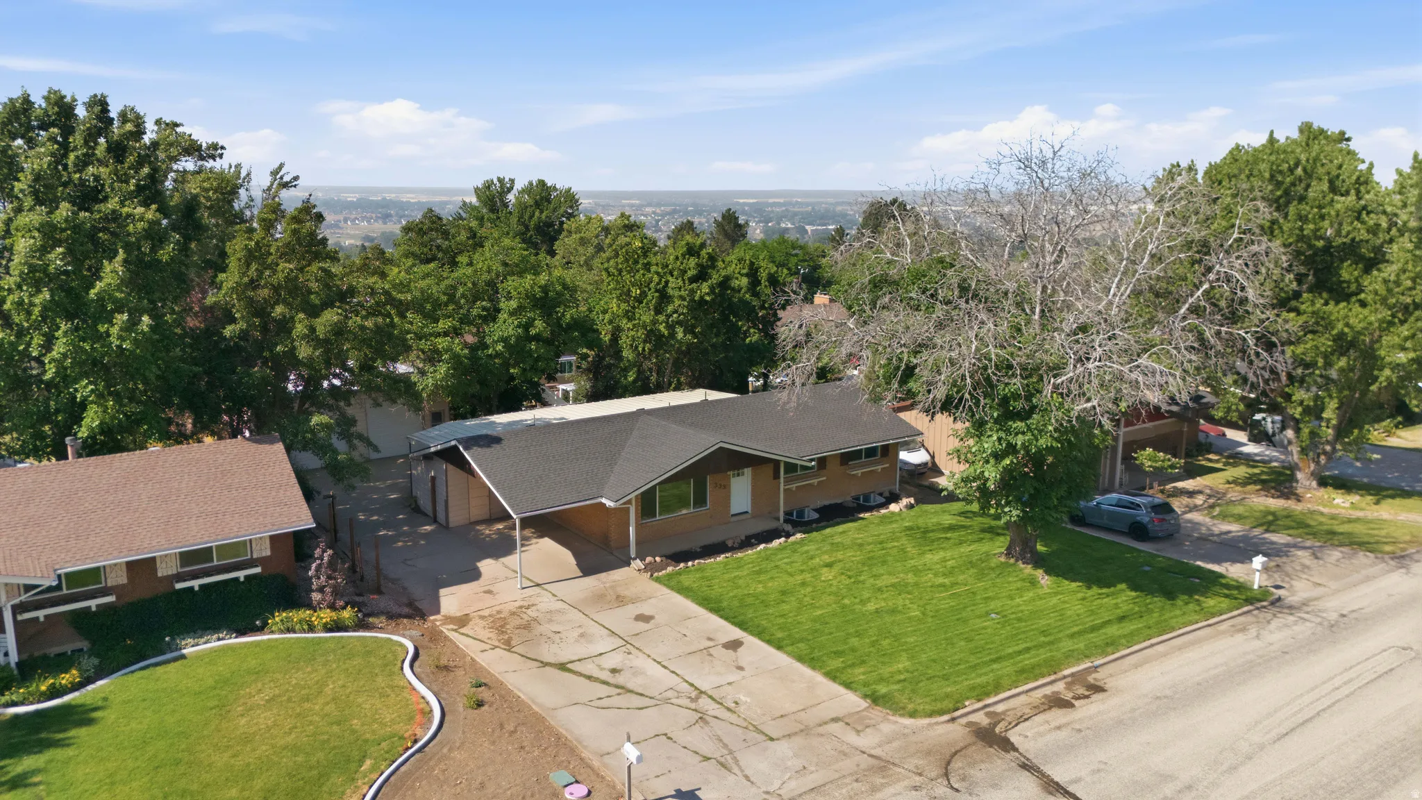 Ranch-style residence featuring a sloped roofline, attached carport, and a paved driveway
