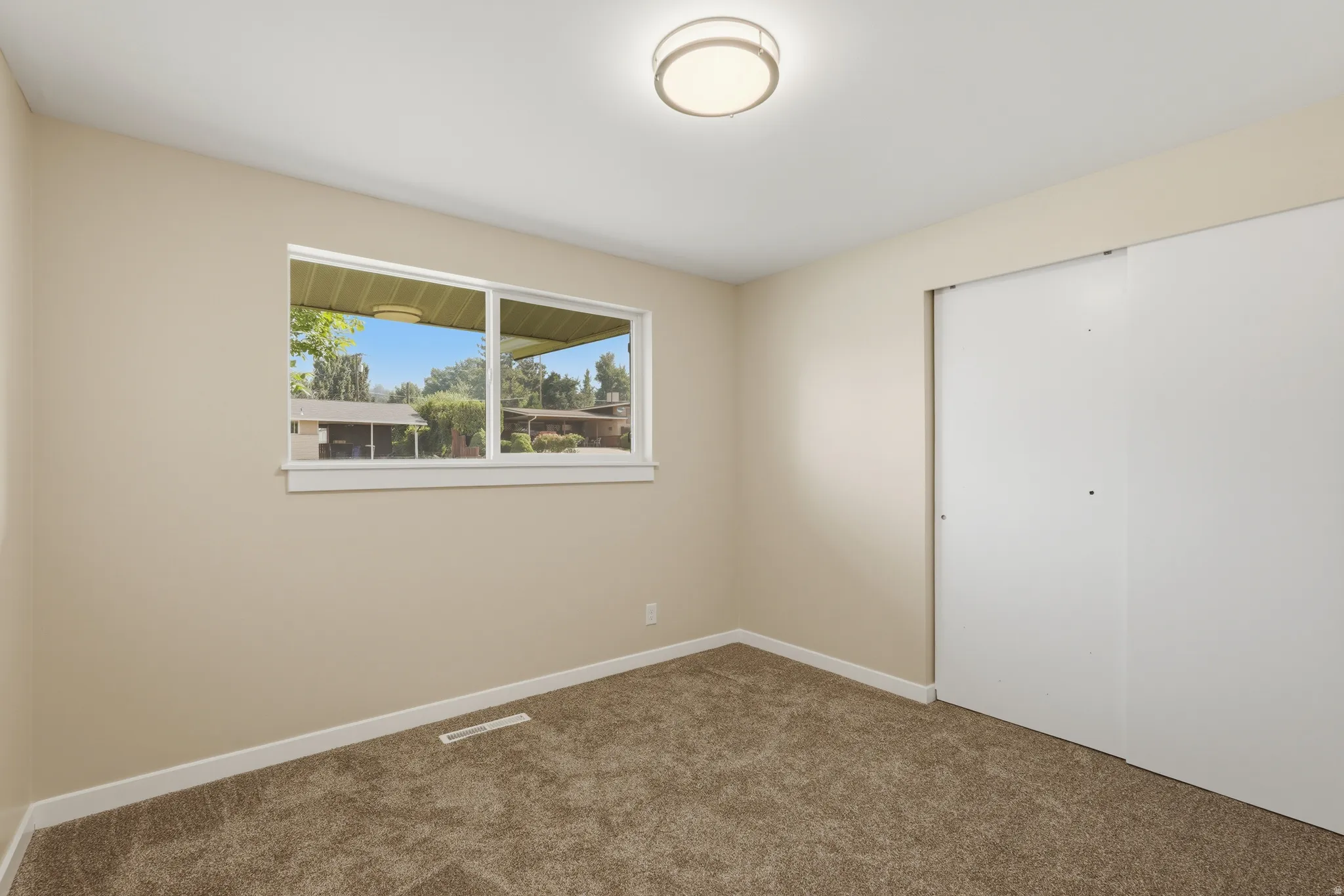 Room featuring neutral wall paint, white trim, a flush-mount ceiling light, and brown carpet flooring