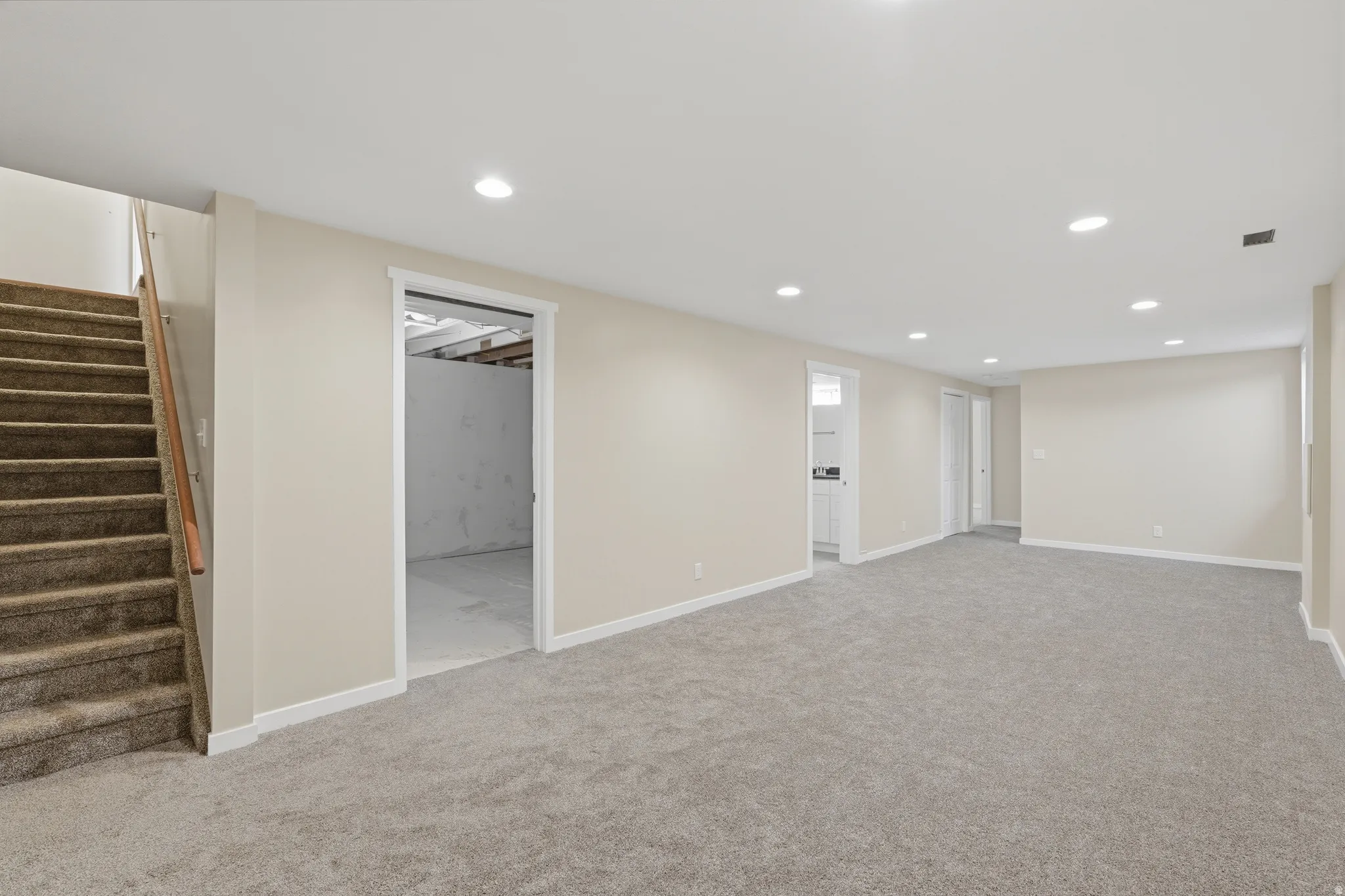 Spacious room featuring neutral carpeting, light-toned wall paint, recessed lighting, and white trim