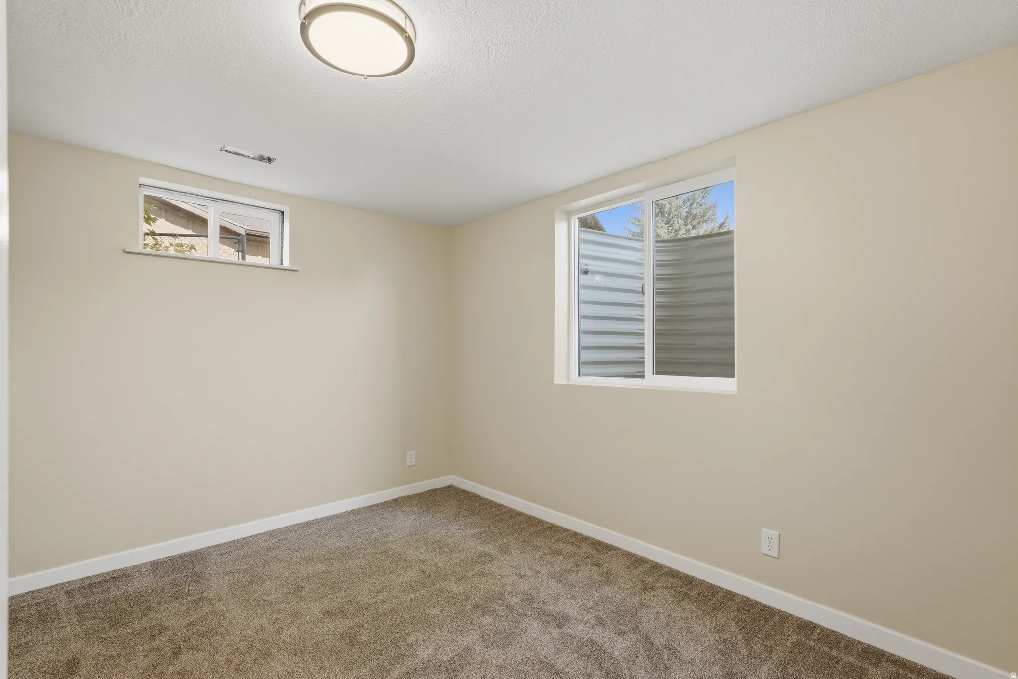 Neutral-toned room featuring plush carpet flooring and white baseboards