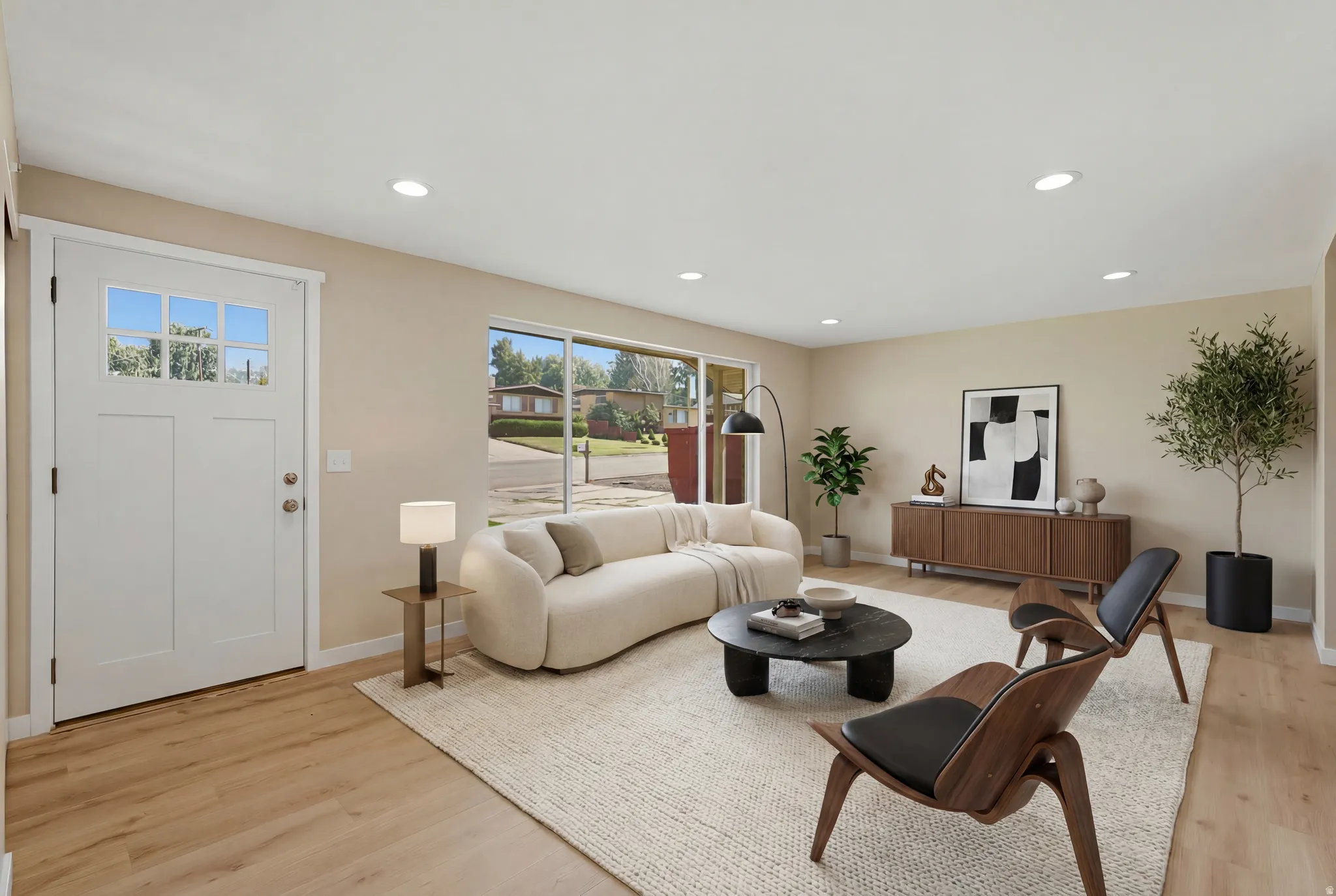 Spacious living area featuring light wood-finish flooring, recessed lighting, and a prominent picture window. Virtually Staged