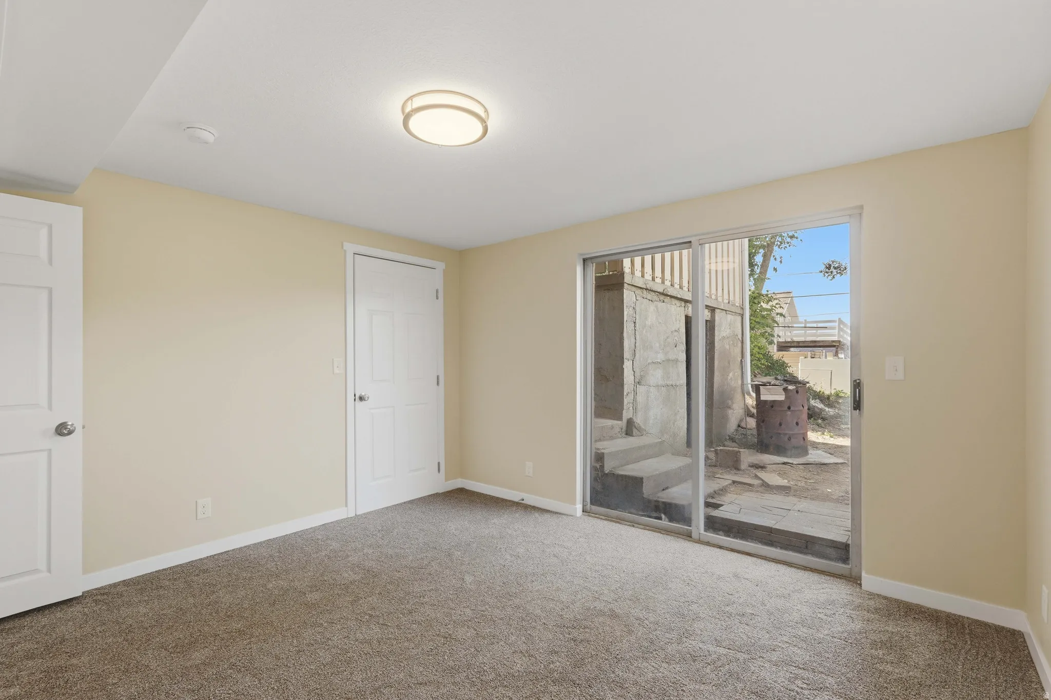 Carpeted room featuring a ceiling-mounted light fixture and sliding glass door