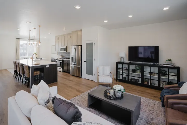 Open-concept living space featuring wood-finish flooring, recessed lighting, and a white color palette