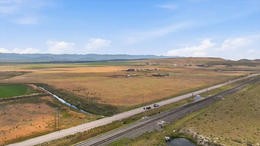 Expansive rural landscape featuring a paved road, railroad tracks, and natural water features