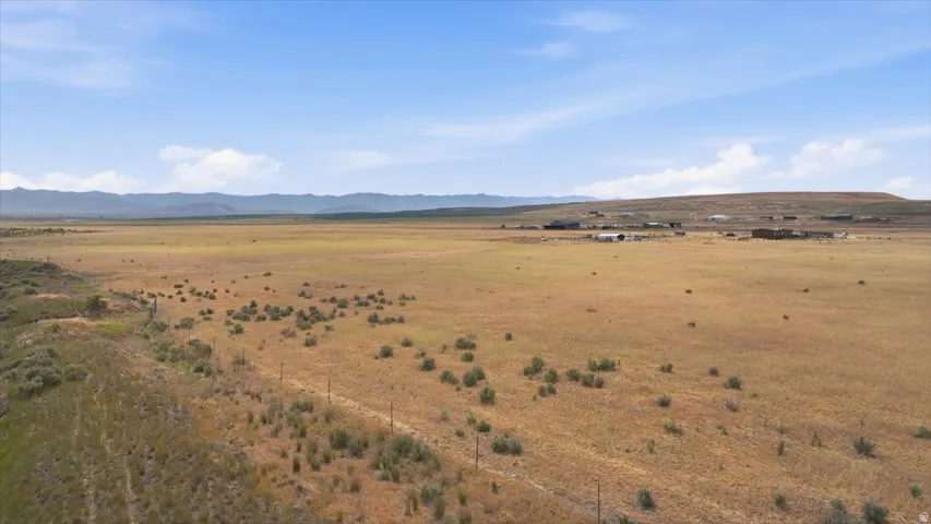 Expansive open land with distant mountain ranges and a clear sky overhead