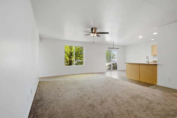 Open-concept living area featuring a ceiling fan, a large window, and sliding glass doors
