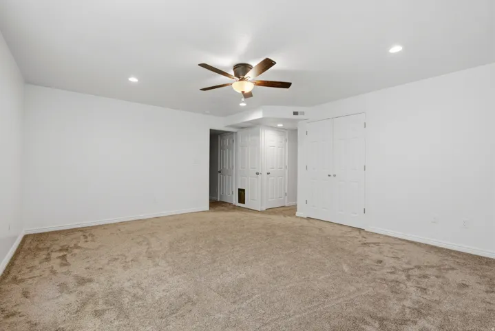 Spacious room featuring neutral carpet, white walls, recessed lighting, and a ceiling fan with integrated lighting