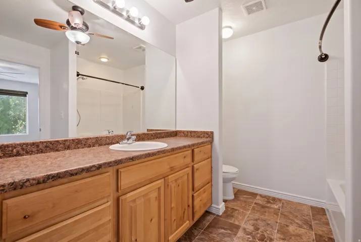 Bathroom featuring a wood vanity with an oval sink, a speckled countertop, and a large wall mirror