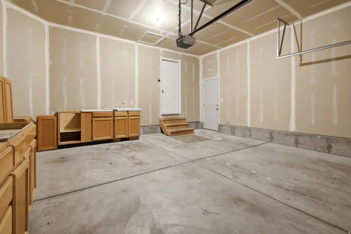 Spacious garage featuring a concrete floor, light-toned walls, two entry doors, and a garage door opener system