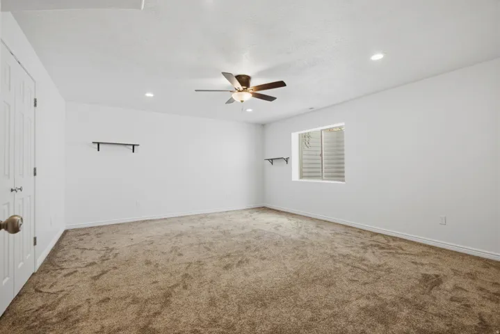 Spacious room featuring neutral carpeting, recessed lighting, and a ceiling fan