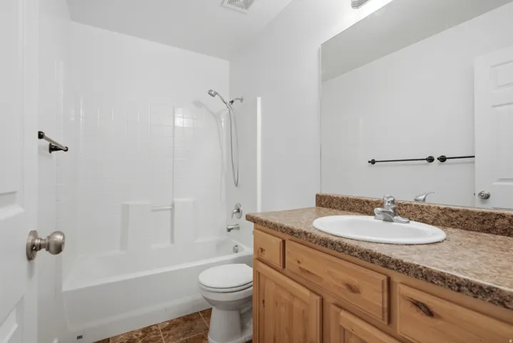 Bathroom featuring a vanity with a laminate countertop, integrated sink, and wood-finish cabinetry