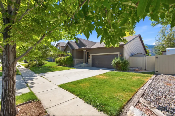 Single-story residence featuring a two-car garage, stone and siding exterior, and a concrete driveway