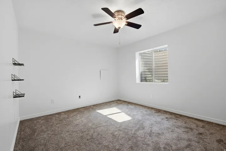 Carpeted room with a ceiling fan light fixture
