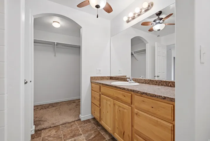 Bathroom featuring a single vanity with a laminate countertop, light wood-finish cabinetry, and a full-width mirror