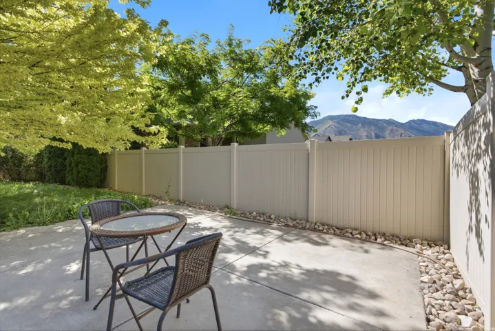 Concrete patio with a privacy fence, mature trees, and mountain scenery