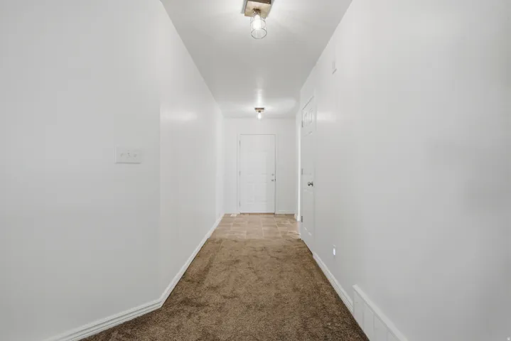Entryway featuring a white paneled door, flush-mount lighting, and a combination of carpet and tiled flooring
