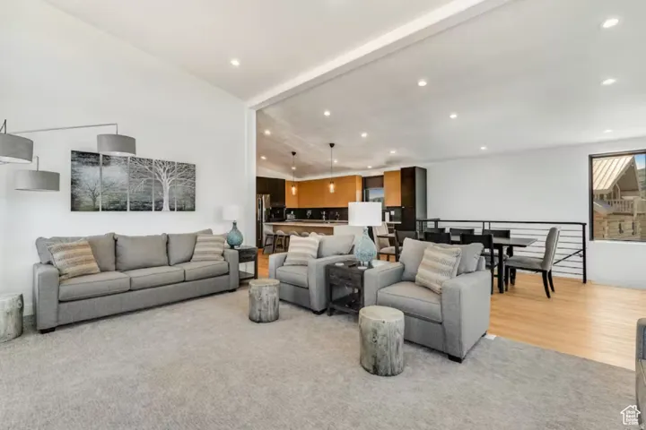 Open-concept main living area featuring high vaulted ceilings, recessed lighting, and a soft gray carpet