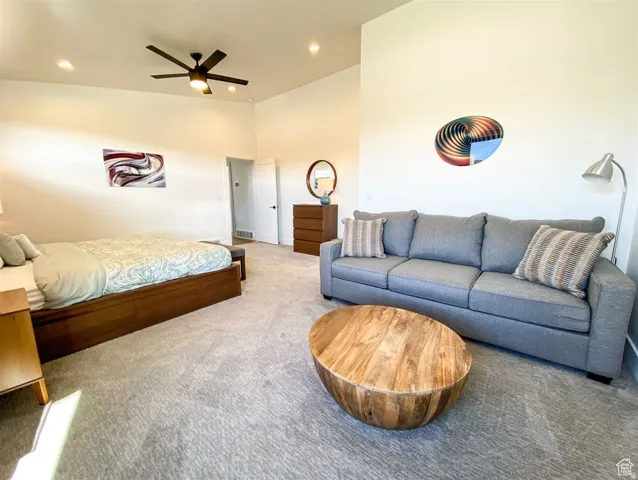Spacious room featuring vaulted ceilings, recessed lighting, a modern ceiling fan, white walls, and light-toned carpet flooring