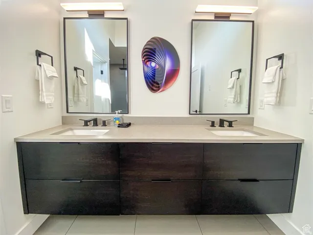 Dual floating vanity featuring dark wood-finish cabinetry, integrated sinks, a light-toned countertop, and matte black fixtures