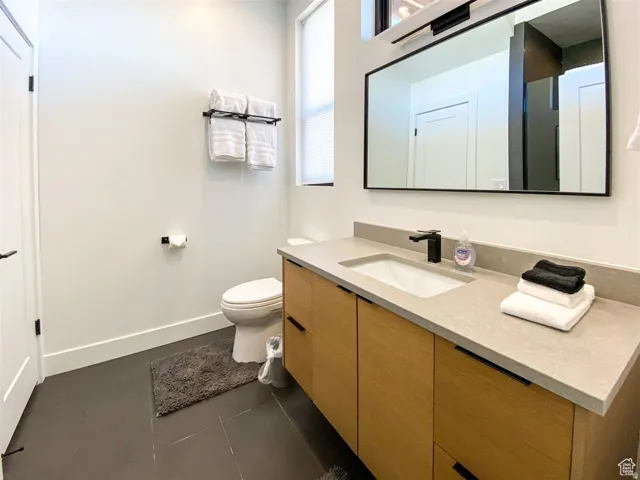 Bathroom featuring a light wood-finish vanity with an integrated sink, matte black faucet, and a large framed mirror