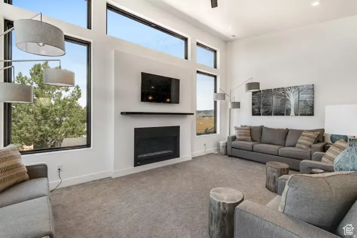 Spacious living area featuring a built-in fireplace, high ceilings, multiple large windows, recessed lighting, and soft gray carpeting