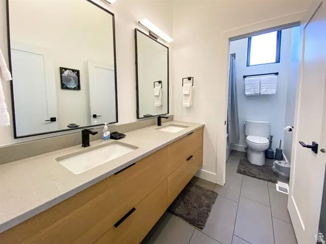 Dual sink vanity featuring matte black fixtures and light wood-finish cabinetry